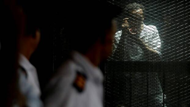 Egyptian photojournalist Mahmoud Abu Zeid, also know as Shawkan, reacts behind a fence during his trial in Cairo, Egypt July 28, 2018