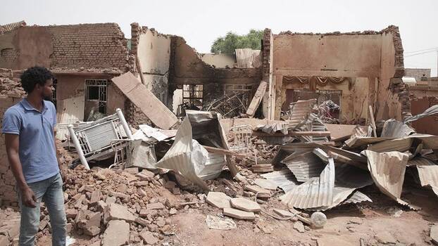 A man walks by a house hit during fighting in Khartoum, Sudan.