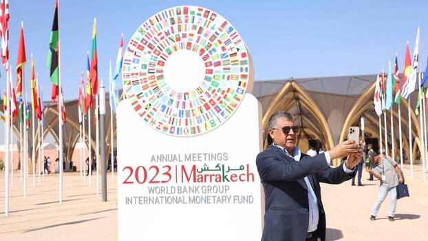 A participant takes a selfie with the logo of the World Bank Group and International Monetary Fund (IMF) annual meetings in Marrakech, Morocco, 9 October 2023.