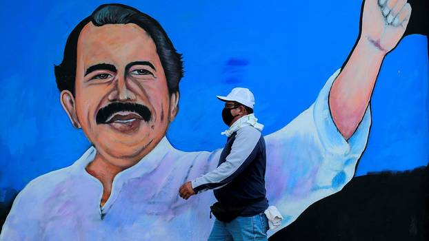 Ein Mann, mit Mund-Nasenschutz geht an einem Wandbild vorbei, das den nicaraguanischen Präsidenten Daniel Ortega darstellt. Managua, 30. März 2020Drohungen verhallten ungehört. Das Volk gehorcht nicht mehr!