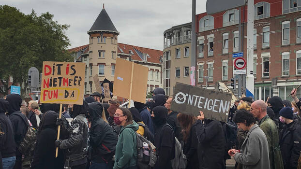 Menschen demonstrieren in Rotterdamm vor Häusern.