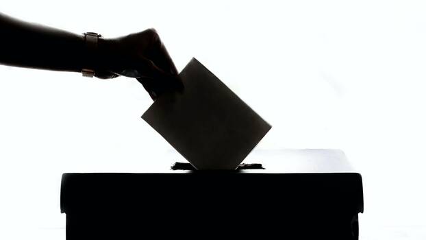 Hand wirft Wahlumschlag in Urne