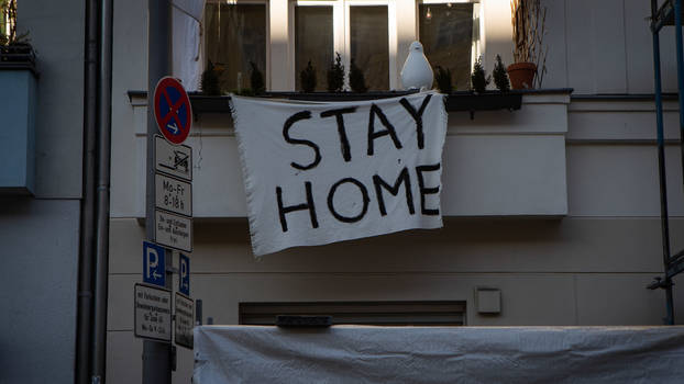 Von einem Balkon in Berlin hängt ein Transparent hängt mit der Aufschrift «Stay home».