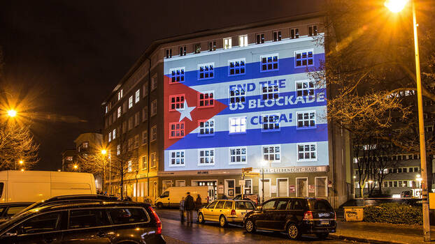 Dezember 2015: Lichtinstallation am Karl-Liebknecht-Haus in Berlin. Man sieht die Kubanische Flagge mit der Aufschrift: "End the US-Blockade". Aktion zur Solidarität mit Kuba. Seit mehr als 60 Jahren versuchen die USA Kuba wirtschaftlich und politisch zu isolieren. 