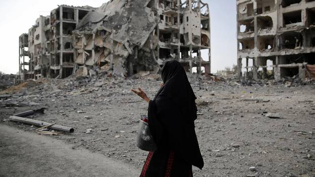 A woman stands among the rubble in Gaza.