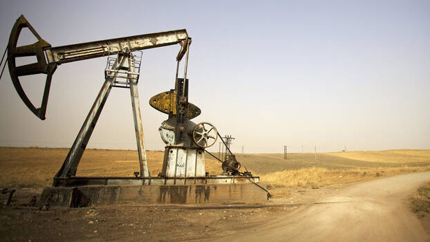 A large oil pump on the edge of a sand road.