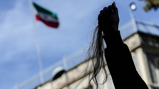 An Iranian woman holds piece of her hair she cuts off, during a protest outside the Iranian Consulate following the death of Mahsa Amini, in Istanbul, Turkey, 26 September 2022.