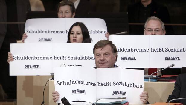 Die Fraktionsmitglieder der hessischen Partei Die Linke halten am 15.12.2010 im Landtag in Wiesbaden Plakate mit der Aufschrift "Schuldenbremse heißt Sozialabbau" hoch. 