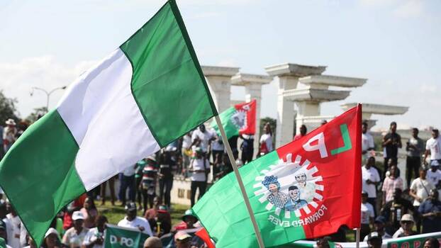 A mass of people holds up Nigerian and Labour Party flags.