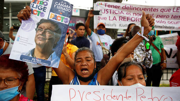 Eine Frau hält ein Wahlplakat mit dem Bild von Gustavo Petro, einem linken Kandidaten für die Präsidentschaftswahl 2022 in Kolumbien nach oben. Neben und hinter ihr sind wietere Unterstützer*innen. Auch sie halten Plakate und Banner.
