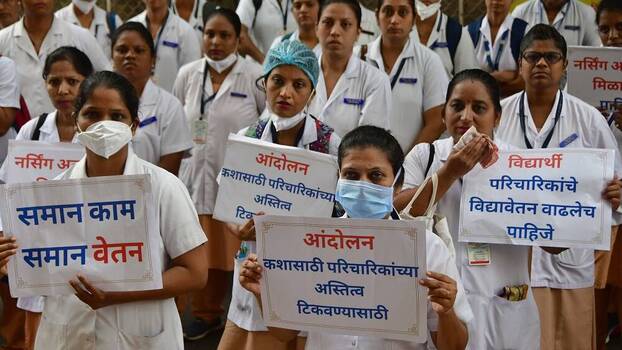 Nurses hold up protest signs in Mumbai, India.