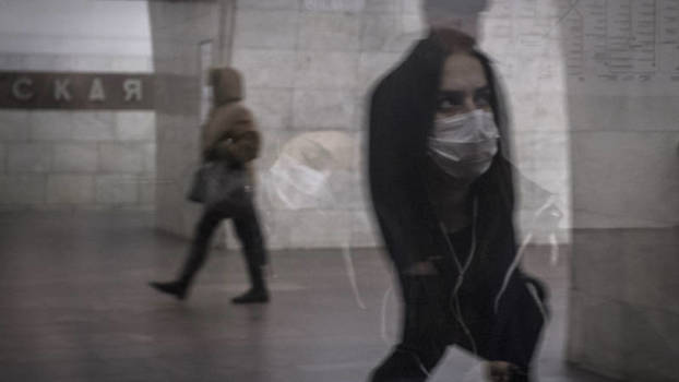 Frau mit Atemmaske spiegelt sich in einer Fensterscheibe, Moskauer Metro, 24.3.2020