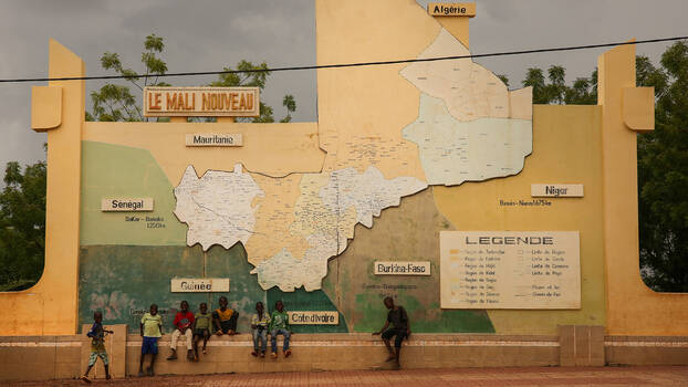 [Translate to en:] Jugendliche sitzen vor eine großen Landkarte aus Beton. Sie zeigt Mali und die Nachbarländer.