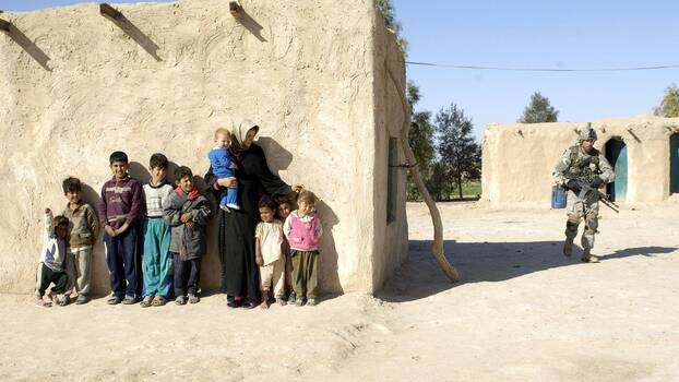 26. März 2006: Eine irakische Familie wartet draußen, während US-Soldaten ihr Haus in der Provinz Salah Ad Din, Irak, durchsuchen.