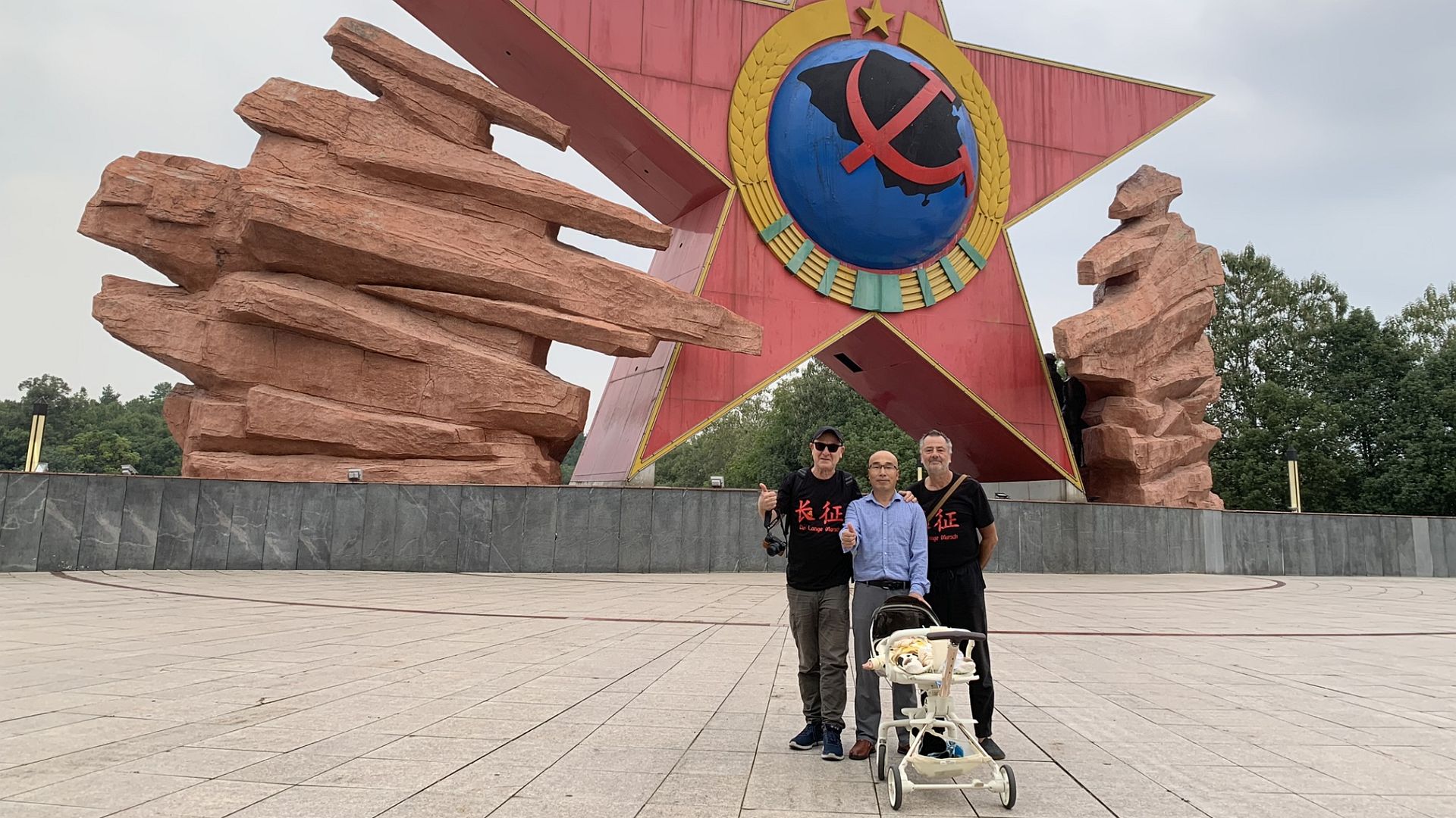 Großvater mit Kinderwagen vor Roter Stern Skulptur in Ruijin, links neben ihm steht Christian Y. Schmidt, rechts Volker Häring