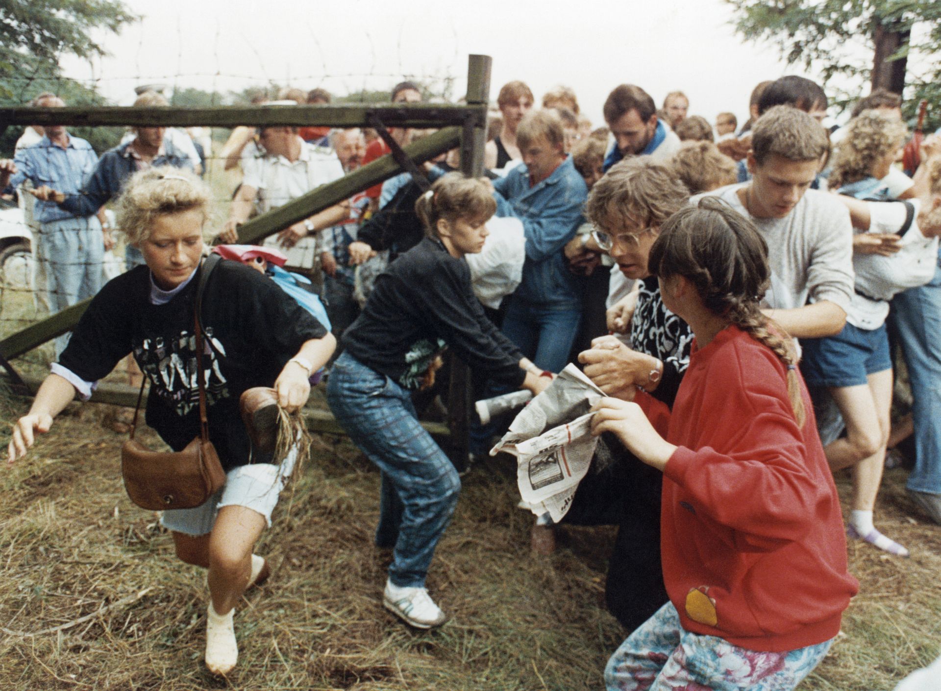 19. August 1989: DDR-Bürger*innen drängen sich bei Sopron in Ungarn durch das offene Gatter über die Grenze nach Österreich.