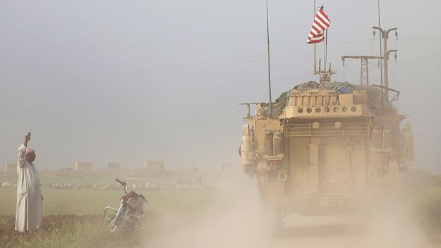 Ein Mann winkt US-Militärfahrzeugen, die in der Stadt Darbasiya (Nordwesten von Syrien) an der türkischen Grenze patroullieren.